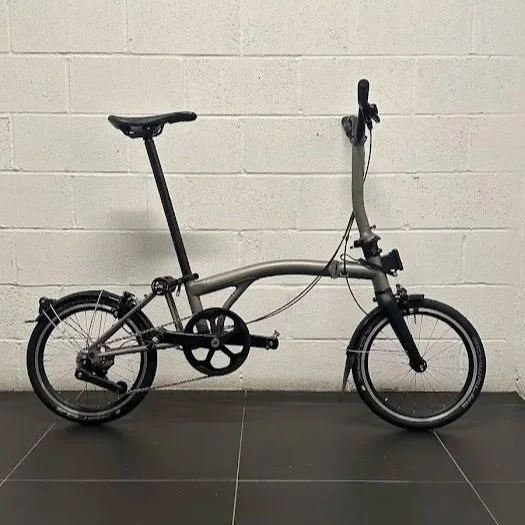 Titanium Brompton T-Line against a white brick wall